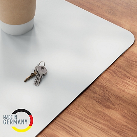 Hellgraue Schreibtischunterlage mit einem Kaffeebecher, Schlüsseln und dem Schriftzug "Made in Germany".