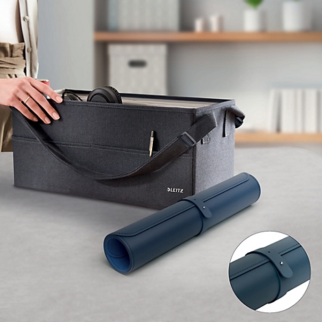 Tapis de bureau roulé bleu foncé avec fermeture en cuir. A côté, une boîte de rangement grise.