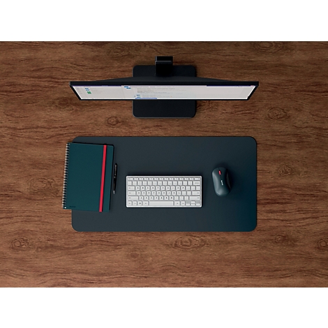 Vue de dessus d'un bureau avec moniteur, souris, clavier, bloc-notes et stylo. Les éléments sont sur un tapis de bureau sombre.