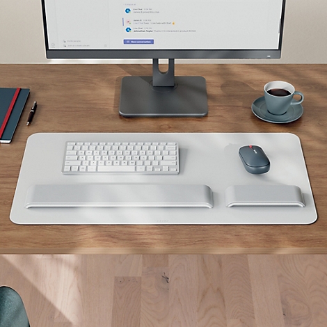 Configuration de bureau avec tapis de souris, clavier, souris, moniteur et tasse de café. Le tout dans des couleurs claires.