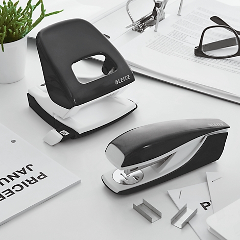 Black and white hole punch and stapler by Leitz on a desk.