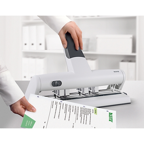 Person punching paper with a white Leitz punch.