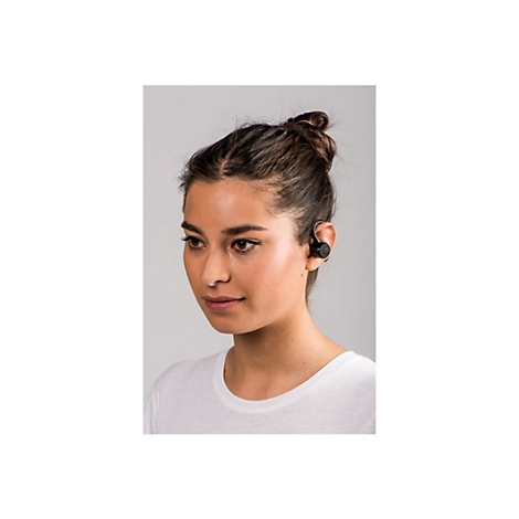 Junge Frau mit hochgesteckten Haaren trÃ¤gt KopfhÃ¶rer im Ohr. Sie blickt zur Seite und trÃ¤gt ein weiÃŸes Shirt.