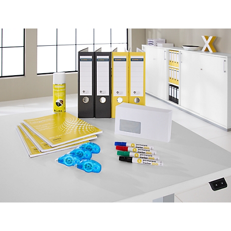 Escritorio con carpetas amarillas, blocs de notas, bolígrafos, barras de pegamento y sobre.