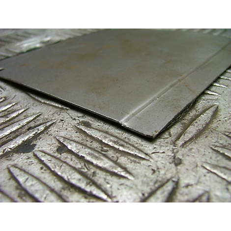 Nahaufnahme eines Metallblechs. Die Oberfläche ist matt, mit einer geprägten, diamantförmigen Textur.