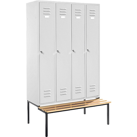 Gray locker cabinets with four doors stand on a bench. The bench has a wooden surface and black legs.