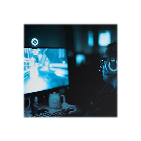 Ein Gamer mit Headset und Brille sitzt vor einem beleuchteten Bildschirm. Der Raum ist dunkel gehalten.