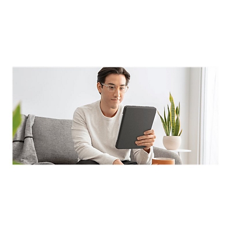 Ein Mann mit Brille sitzt auf dem Sofa und schaut auf ein Tablet. Im Hintergrund eine Pflanze.