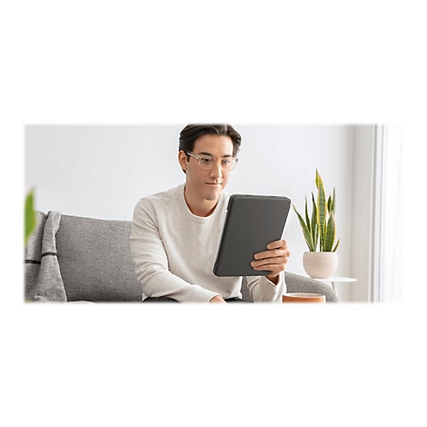 Ein Mann mit Brille sitzt auf einem Sofa und hält ein Tablet. Auf dem Beistelltisch steht eine Pflanze.