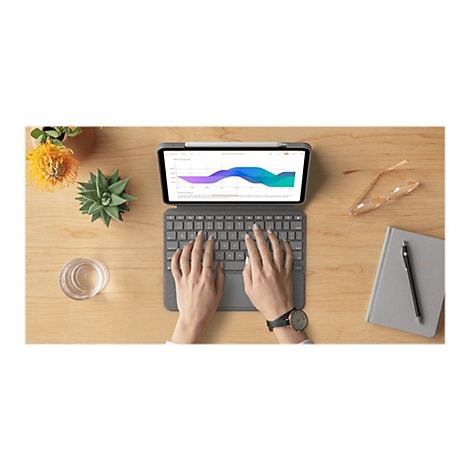 Person tippt auf einer Tastatur. Auf dem Tablet wird ein Diagramm angezeigt. Daneben liegen Brille, Notizbuch und Pflanze.