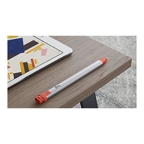 Un stylet argentÃ© avec des dÃ©tails orange est posÃ© Ã  cÃ´tÃ© d'une tablette sur une table en bois. Un motif colorÃ© est visible sur la tablette.