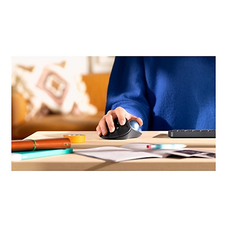 Gros plan d'une main actionnant une souris ergonomique. D'autres articles, un clavier et des notes sont sur la table.