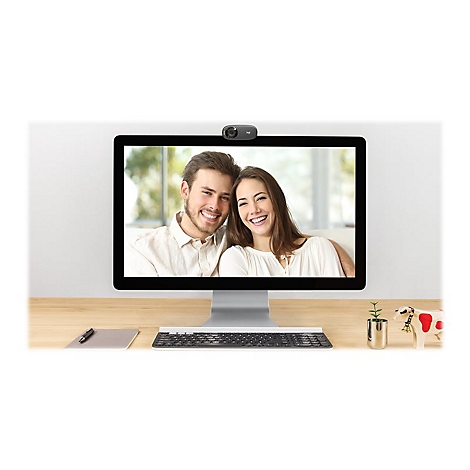 Ein Monitor zeigt ein lÃ¤chelndes Paar bei einem Videoanruf. DarÃ¼ber sitzt eine Webcam.