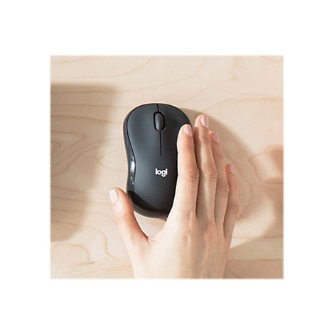 Eine Hand liegt neben einer schwarzen Logitech-Maus auf einer HolzoberflÃ¤che. Das Logitech-Logo ist deutlich sichtbar.