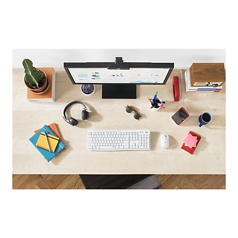 Draufsicht eines Schreibtischs mit Monitor, Tastatur, Maus, KopfhÃ¶rern und diversen BÃ¼roartikeln. Auf dem Monitor sind Diagramme zu sehen.
