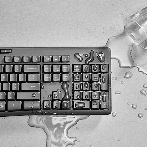 Black keyboard covered in water. An overturned water bottle is next to it.