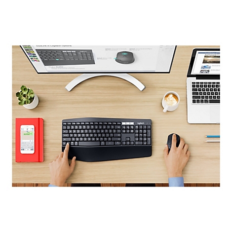 Vue de dessus d'un bureau. Sur la surface en bois se trouvent un clavier, une souris, un smartphone, un ordinateur portable, une tasse de café et une petite plante.