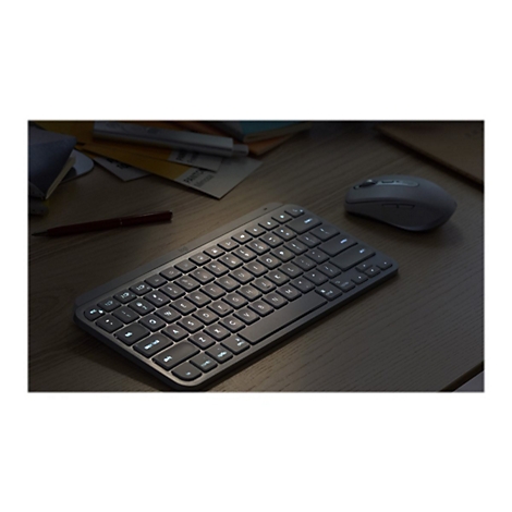 Draufsicht auf eine Tastatur, Maus und Notizen auf einem Schreibtisch. Helle Tasten beleuchten die Szene.