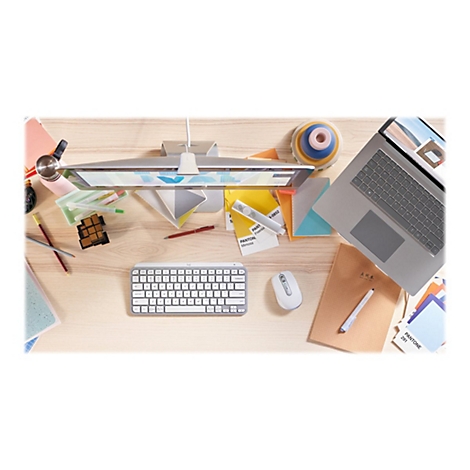 Draufsicht auf einen Schreibtisch mit Computerzubehör, Notizen, Stiften und Laptop. Farben und Texturen sind erkennbar.