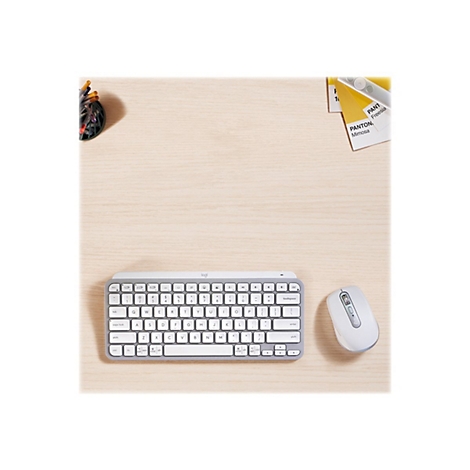 Draufsicht auf ein hellgraues Logitech-Keyboard und eine Maus auf einer Holzoberfläche, daneben Stifte und Farbfächer.