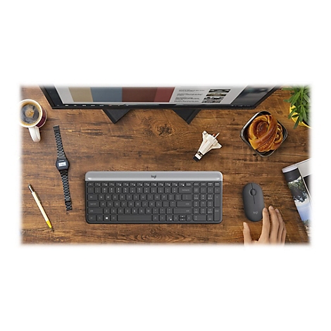 Draufsicht auf einen Schreibtisch mit Tastatur, Maus, Kaffee, Gebäck, Armbanduhr und Monitor.