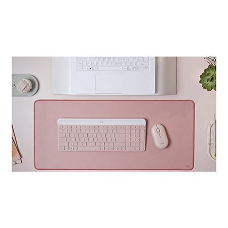 Draufsicht auf einen Schreibtisch mit Tastatur, Maus, Mauspad und Laptop. Alles in Rosa gehalten.