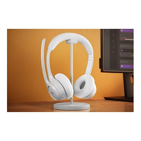 WeiÃŸes Headset mit Mikrofon auf einem StÃ¤nder. Im Hintergrund ein Monitor.