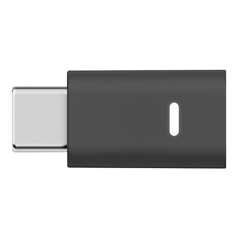 Un adaptateur USB-C noir. Un connecteur argenté entre dans une partie sombre et rectangulaire, avec une lumière ovale blanche.
