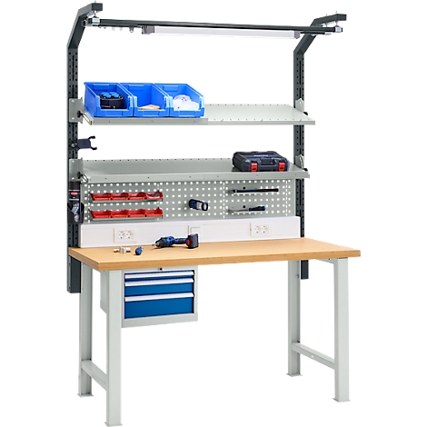 Établi avec éclairage, étagères, tiroirs et panneau perforé, équipé d'outils. Des vis et une visseuse sans fil sont sur la surface de travail.