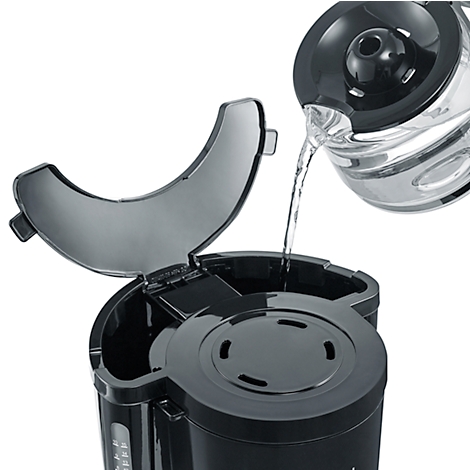 Gros plan sur une cafetière noire. De l'eau est versée dans le réservoir d'eau à partir d'un récipient en verre.