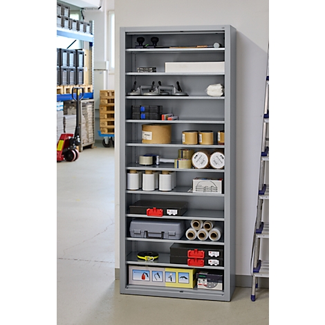 Grauer Werkzeugschrank mit Werkzeugen und Materialien in einer Werkstatt. Dahinter ein Gabelstapler und eine Leiter.