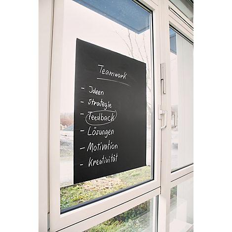 Schwarze Tafel am Fenster, mit weißer Schrift: Teamwork, Ideen, Strategie, Feedback, Lösungen, Motivation, Kreativität.