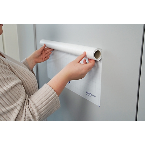 Persoon bevestigt een rol papier aan een muur, het papier heeft een rasterpatroon.