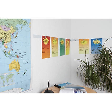 Colorful notes with text hang on a wall, above a world map and a desk.