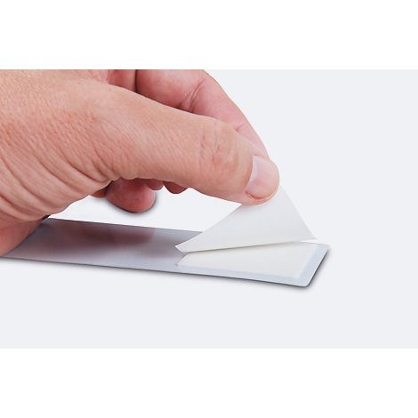 A hand peels a white sticker from a grey strip.