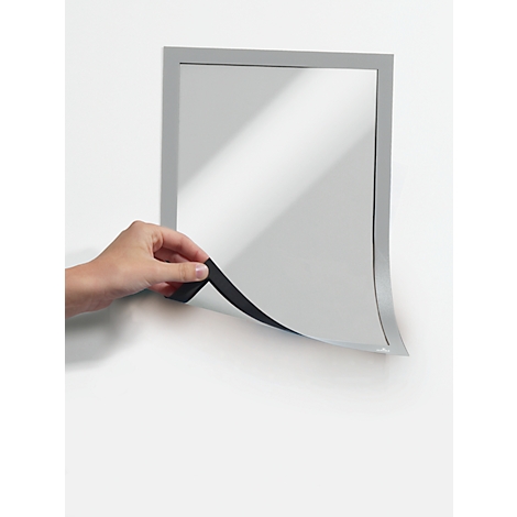 A hand pulls a black strip of a frame away from the wall. The rectangle of the picture underneath is grey.