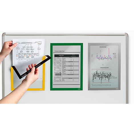 Person attaching a paper with a black frame in a yellow holder to a magnetic board. To the right are documents in green and silver holders.