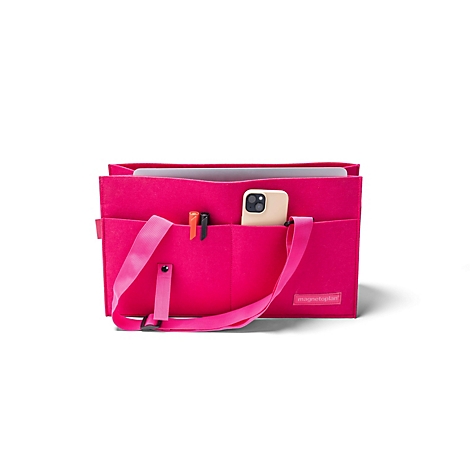 Een roze vilten tas met schouderband, gevuld met een laptop, pennen en een smartphone.