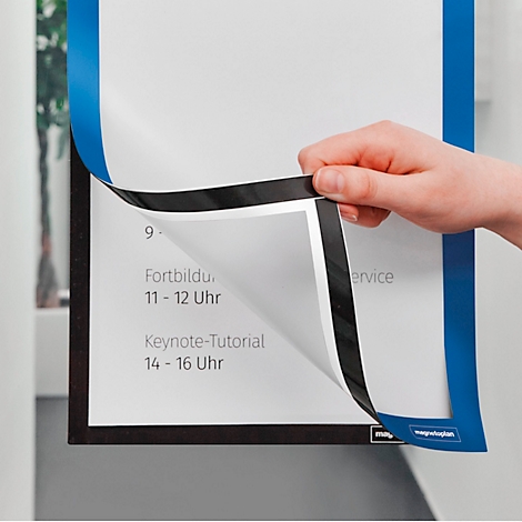 Hand hebt den blauen Rand eines magnetischen Inforahmens an, der einen Terminplan an einer Wand hält.