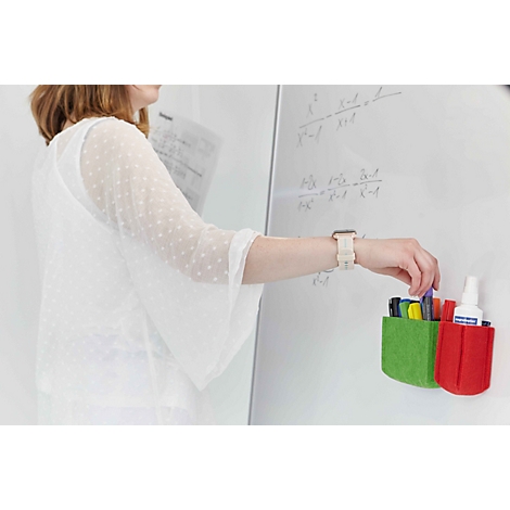 Eine Frau greift an einer Whiteboard-Tafel nach einem Stift aus grünen und roten Filz-Stiftehaltern.