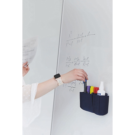 Une main saisit un feutre dans un organisateur en feutre bleu fixé sur un tableau blanc avec des formules mathématiques.