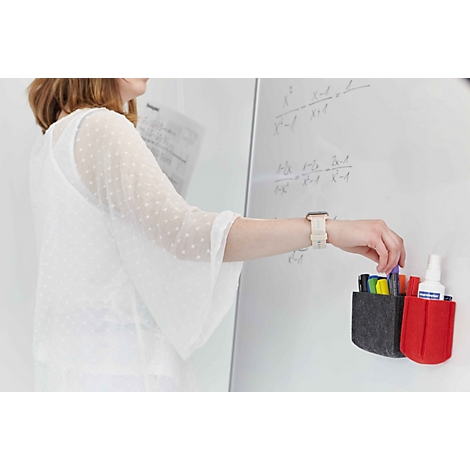 Eine Frau greift an einem Whiteboard nach einem Marker aus einem grauen und roten Filz-Stiftehalter.