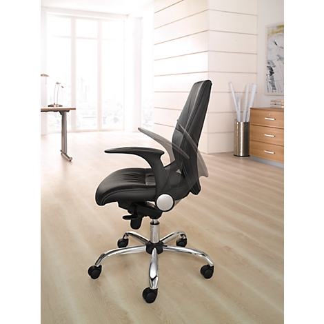 Black office chair with adjustable armrests and backrest. On light-colored floor in front of window and furniture.