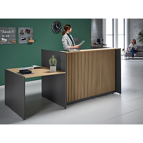 Receptie met houten bekleding, medewerker met tablet, grijze elementen, klok, andere persoon op de achtergrond.