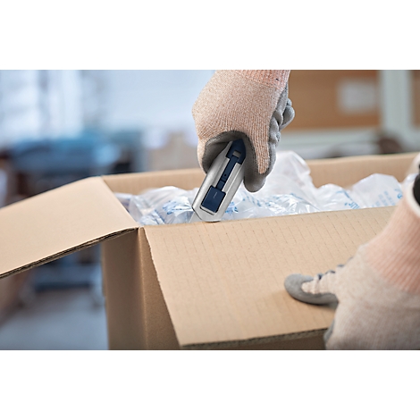 Person in Handschuhen öffnet einen Karton mit einem Cutter.
