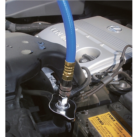 Blauer Schlauch an einem Kühlmittelbehälter im Motorraum eines Autos. Der Deckel wird geöffnet.
