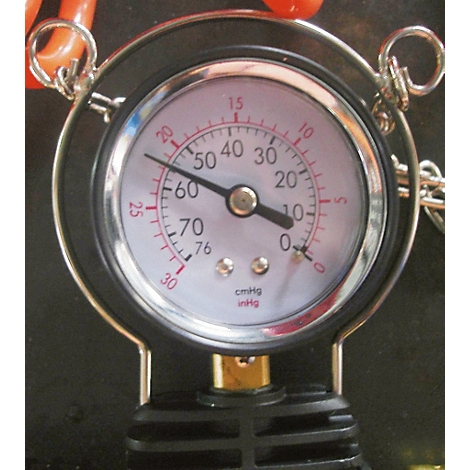 Ein rundes Manometer mit schwarzem Rahmen, weißem Zifferblatt und roter Nadel. Der Zeiger zeigt ca. 10 an.
