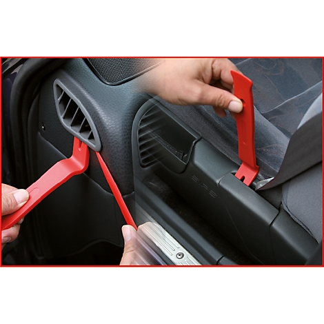 Nahaufnahme einer Person, die mit roten Hebelwerkzeugen an einer Autotür arbeitet. Das Werkzeug wird verwendet, um Verkleidungen zu entfernen.