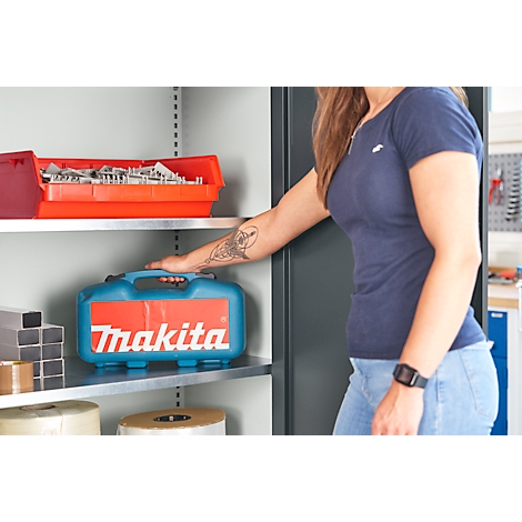 Vrouw grijpt naar een turquoise Makita koffer in een gereedschapskast. Rode bak met schroeven erboven.