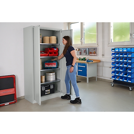 Een vrouw opent een grijze gereedschapskast in een werkplaats. De kast is gevuld met gereedschap en materialen.
